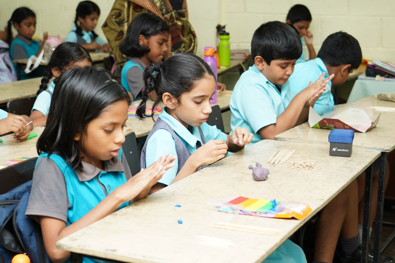 Creative Learning: Students Crafting in Classroom Students crafting with clay and sticks in a classroom.