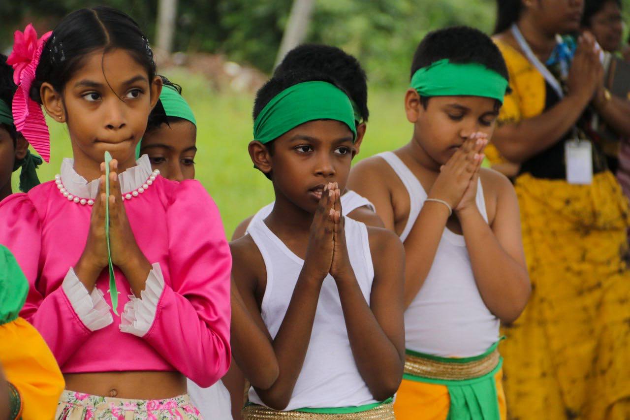 Children in traditional attire engaging in a serene outdoor cultural ceremony with prayerful unity.