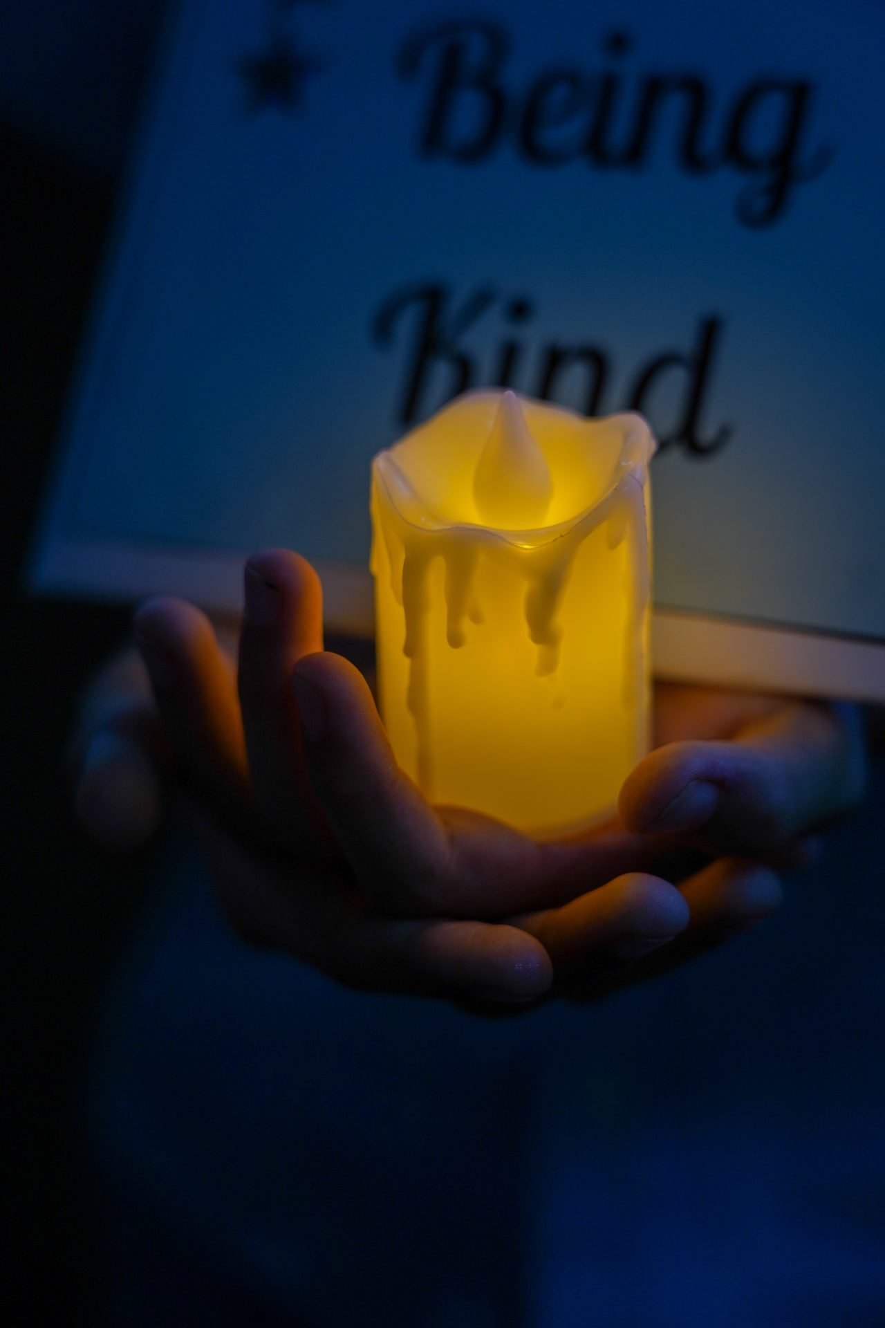 Hand holding candle with warm glow, evoking kindness and mindfulness.
