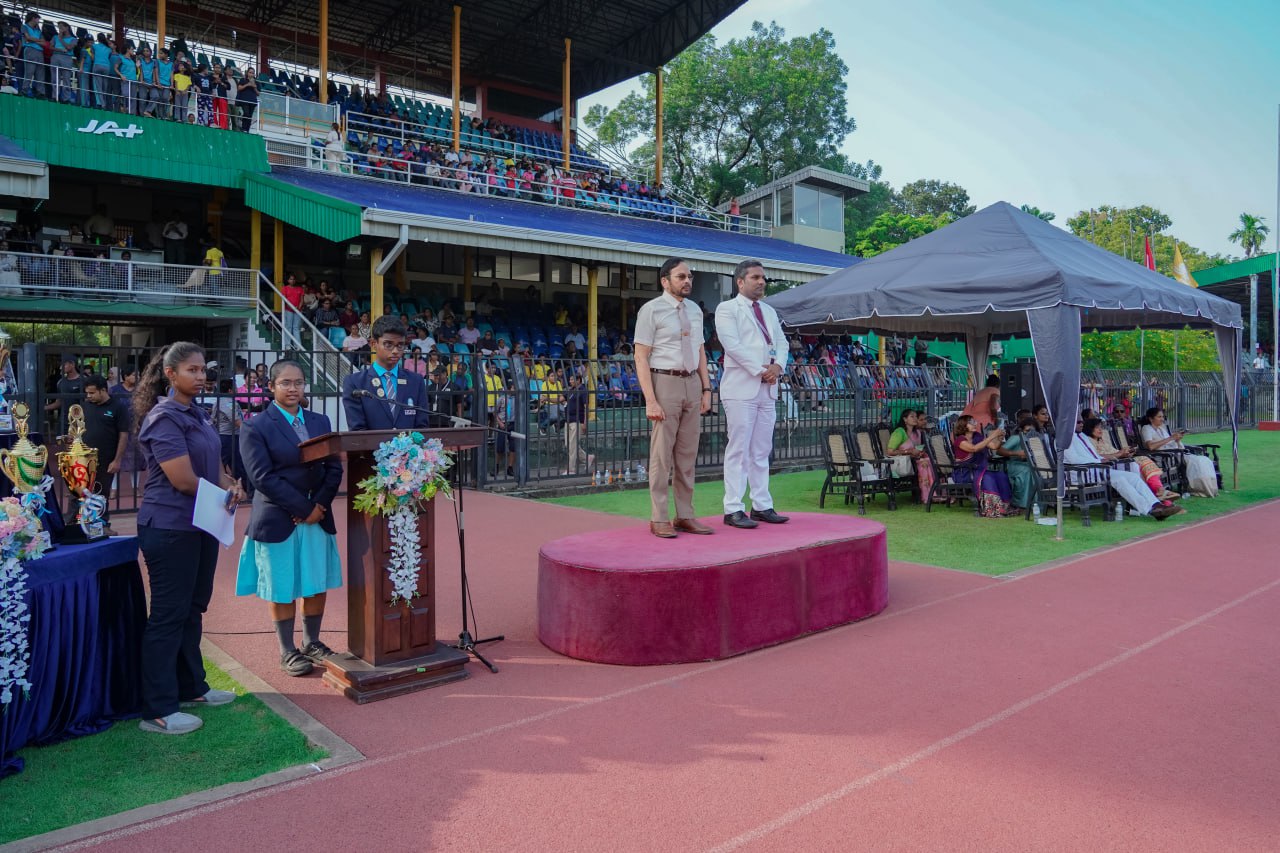 Formal sports field event with podium, dignitaries, and large audience under clear skies.