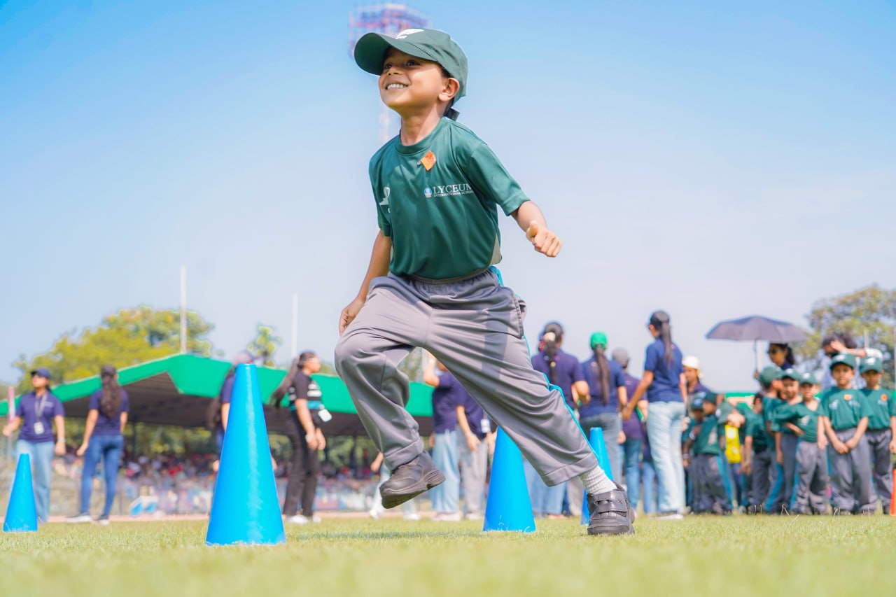Young child leaps over cones at outdoor sports event, showcasing energy and community spirit.
