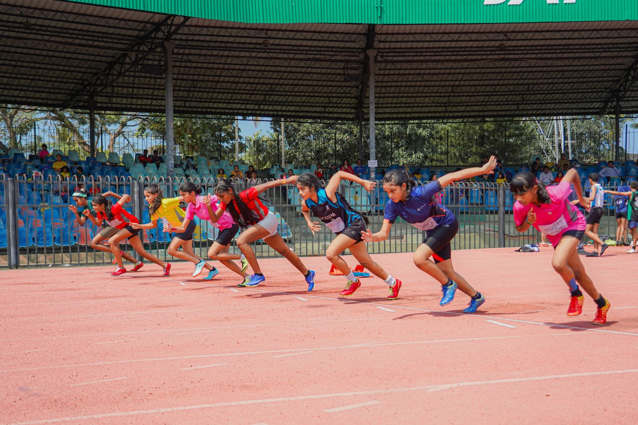Young athletes sprint off the starting line, showcasing vibrant uniforms and intense focus.