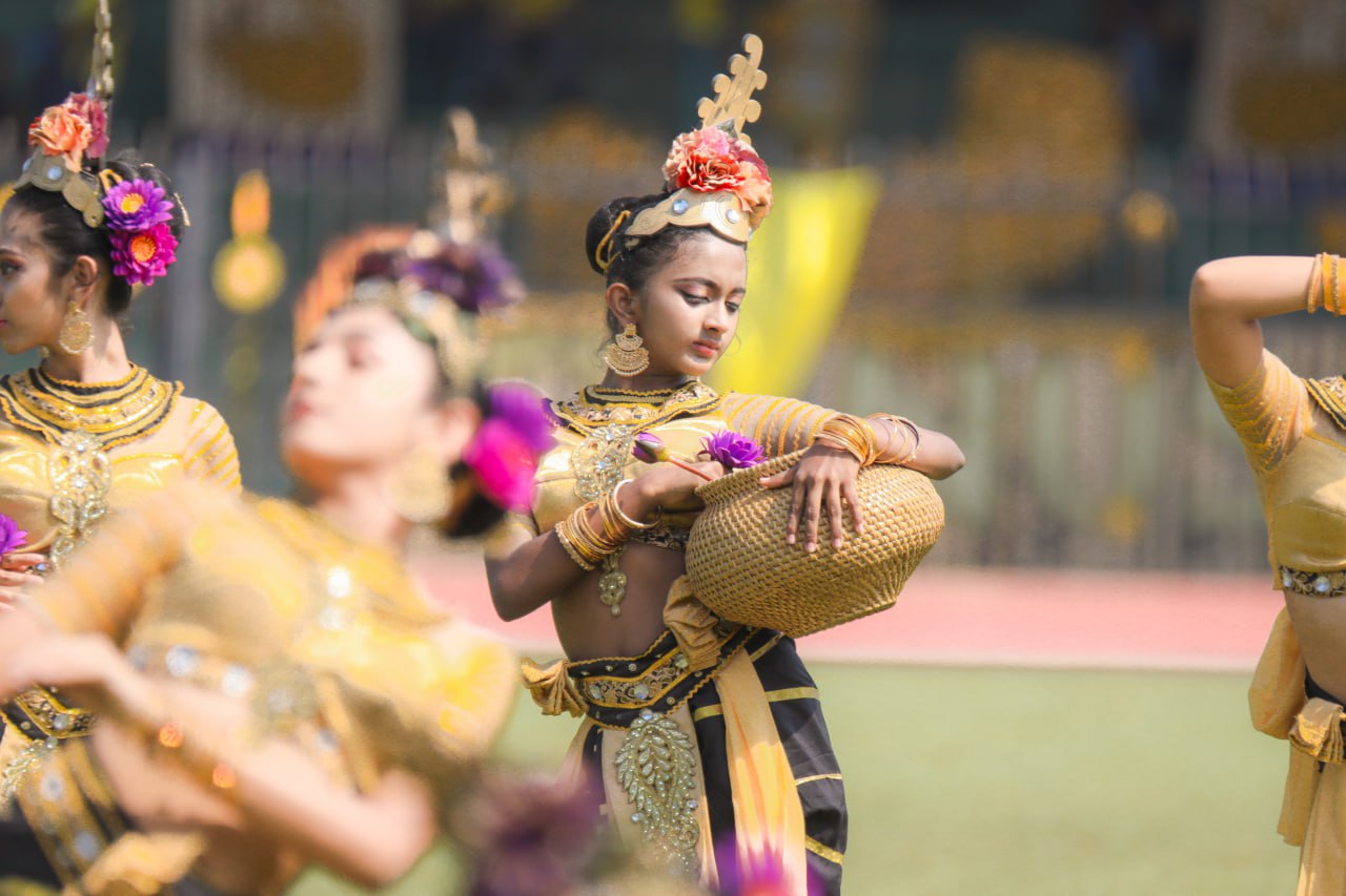 Young women perform vibrant traditional dance in ornate costumes, enhancing cultural elegance outdoors.