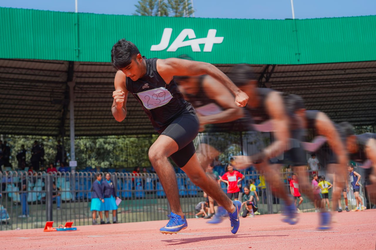 Male sprinter accelerates forcefully on red track, captured with motion blur and focused energy.