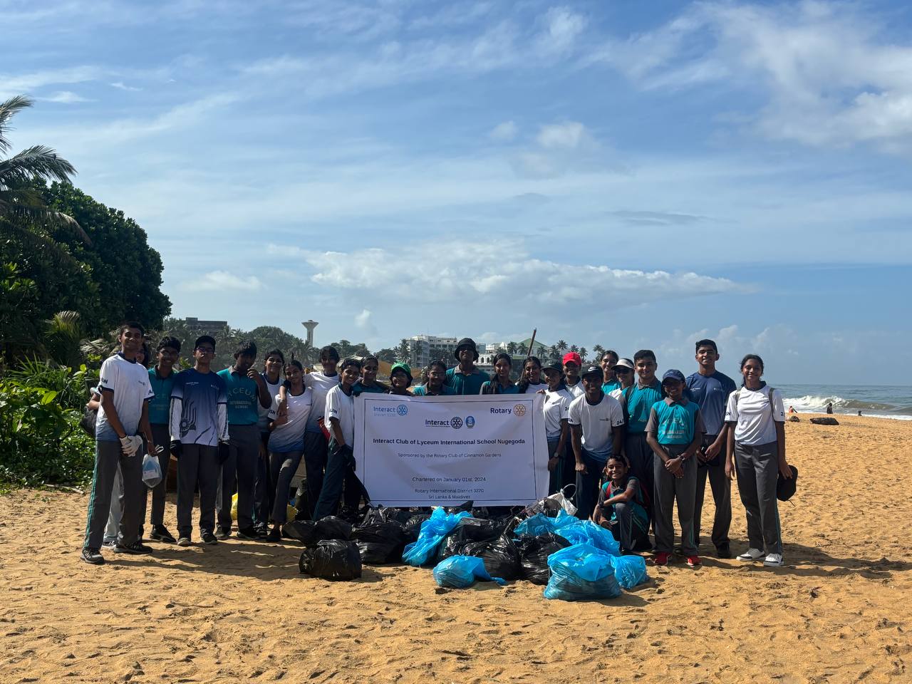 Volunteers at beach cleanup holding banner, showcasing community spirit and environmental conservation efforts.
