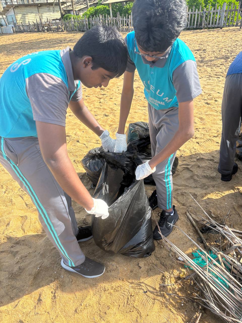 Volunteers in blue uniforms collect beach litter, fostering conservation and community teamwork.