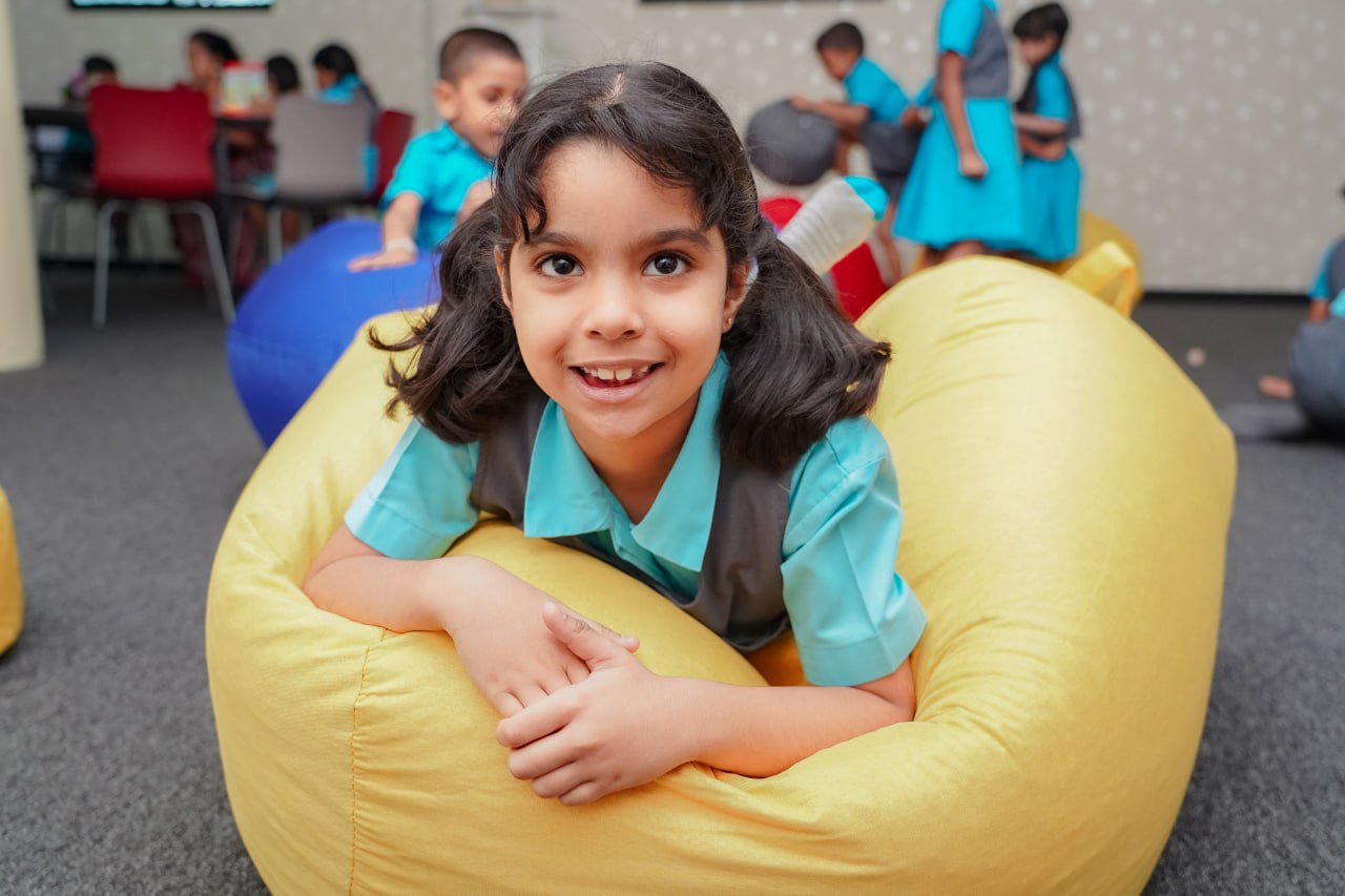 Smiling Girl Enjoying School Bean Bag Fun Smiling girl on yellow bean bag in vibrant classroom setting.