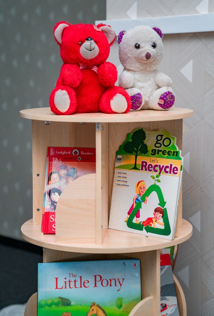 Cozy Childrens Bookshelf with Teddy Bears and Storybooks Childrens wooden bookshelf with teddy bears, eco-friendly books, and storybooks.