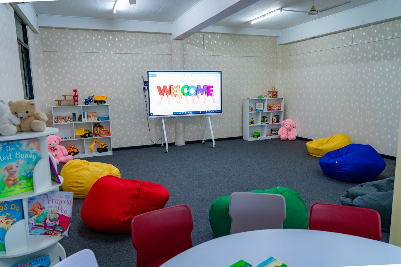 Cheerful Childrens Learning and Play Space Bright playroom with digital welcome, colorful seating, books, toys, and learning materials.