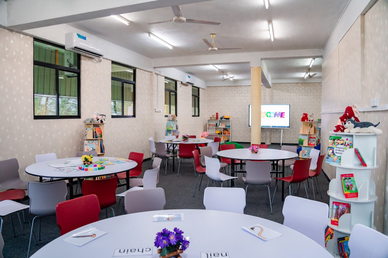 Bright Collaborative Classroom with Modern Educational Tools Bright, airy classroom for collaborative learning with round tables, colorful chairs, and digital screen.