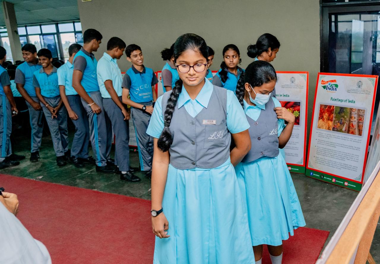 Students in uniforms explore Indian art exhibit, featuring Paintings of India posters.
