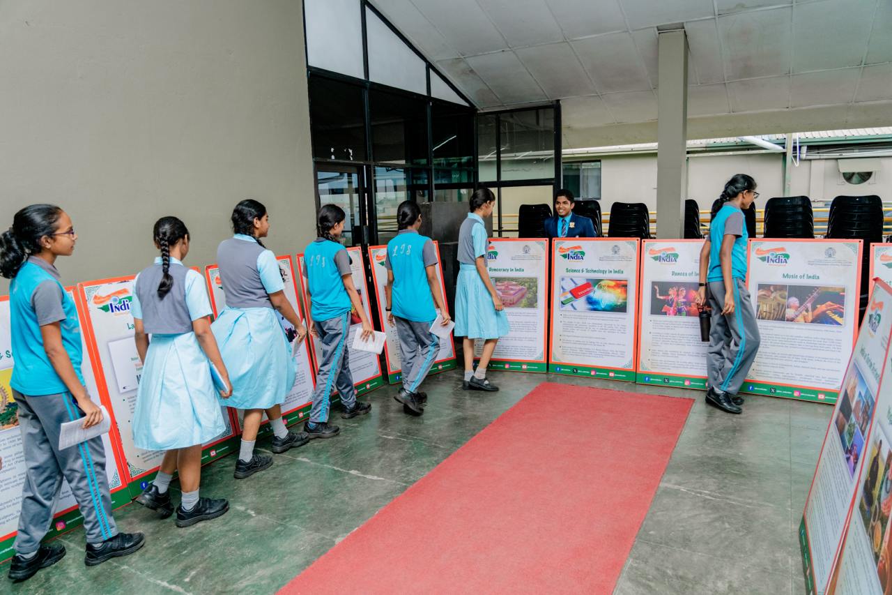Students engaging with vibrant educational posters on Indian culture at school exhibition.