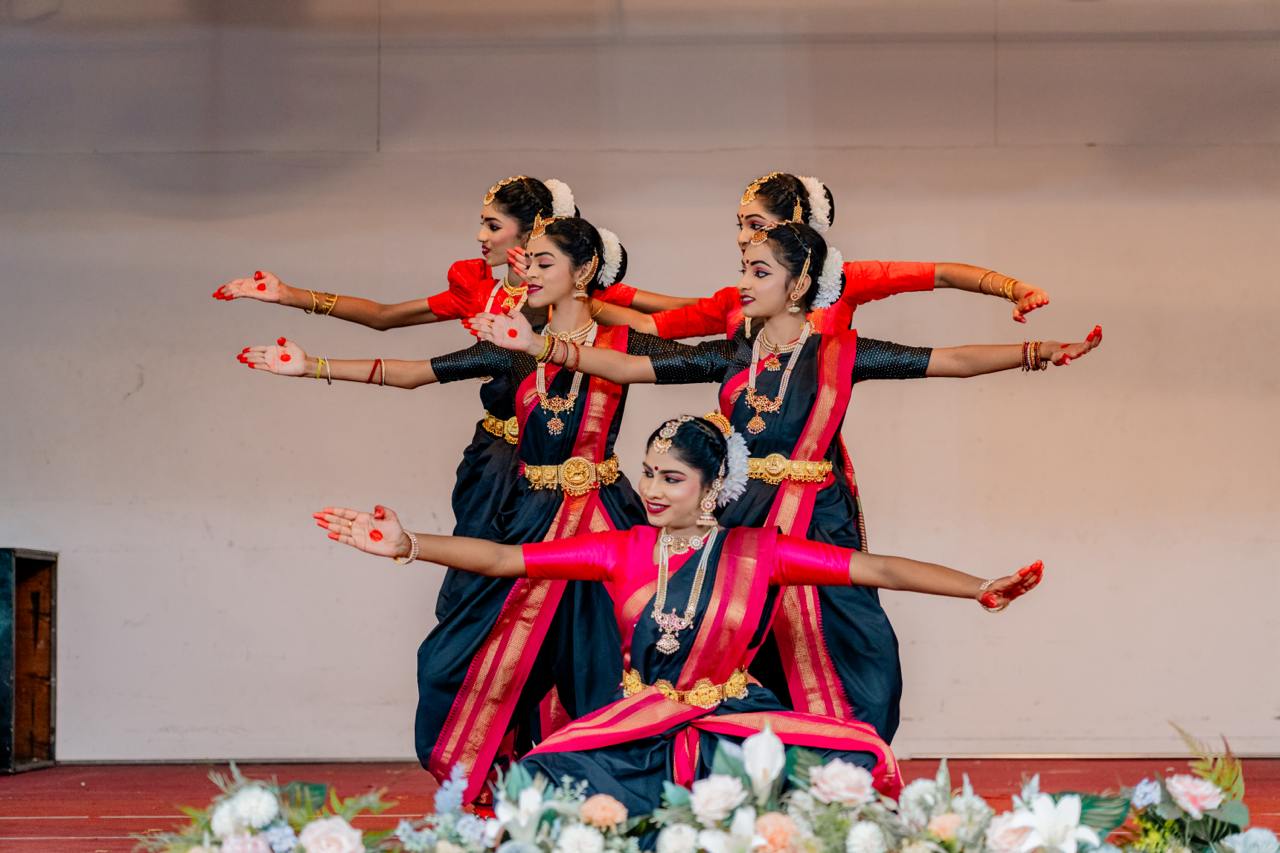 Bharatanatyam dancers in red and black costumes, showcasing grace and cultural elegance on stage.