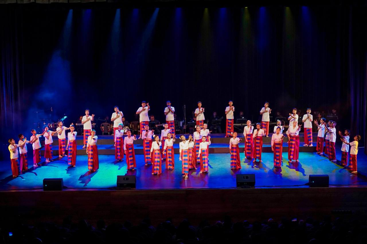Cultural dance performance with red and white costumes, dynamic lighting, and live music.
