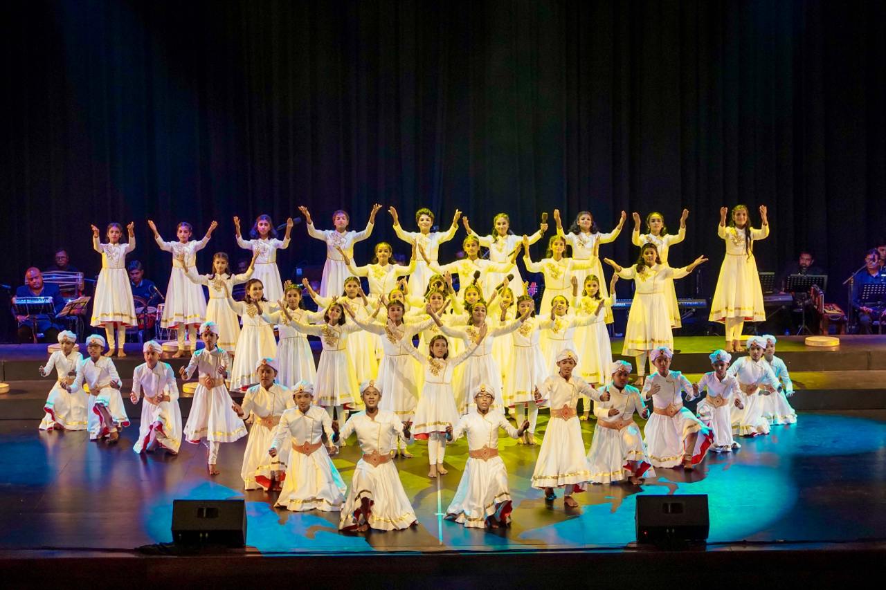 Elegant cultural dance with synchronized performers in white outfits under vibrant stage lighting.