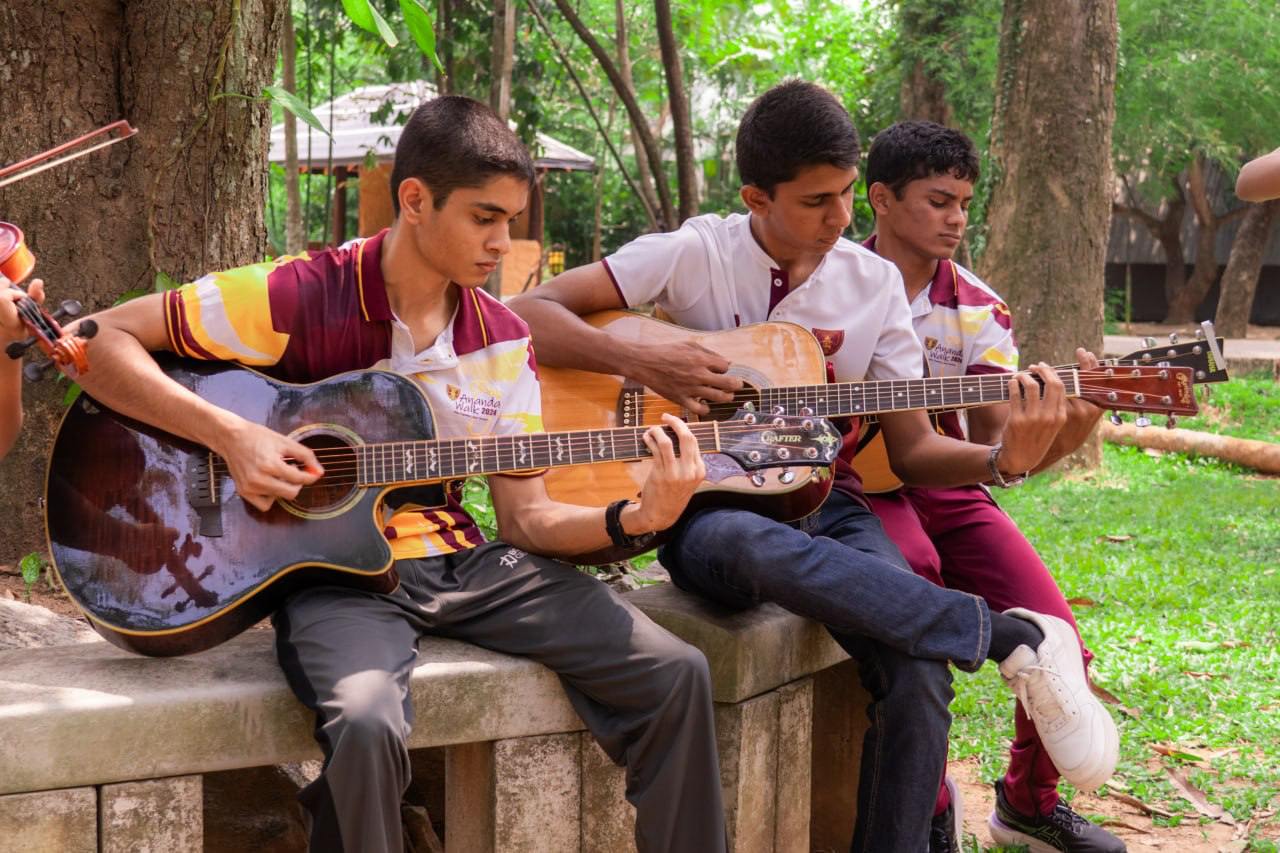 Young musicians in matching uniforms play acoustic guitars in a tranquil park setting.