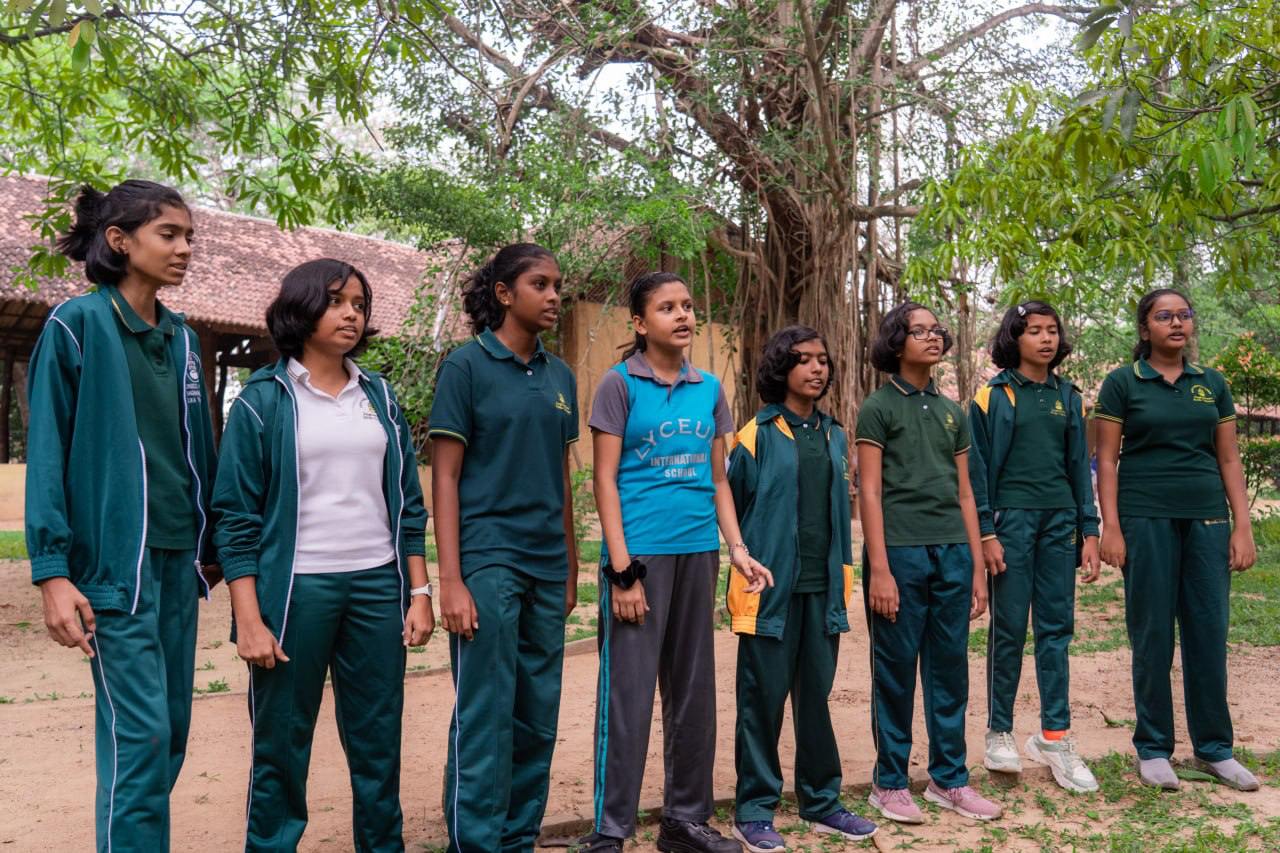 Eight young people in athletic wear attentive in natural setting, ready for outdoor activities.