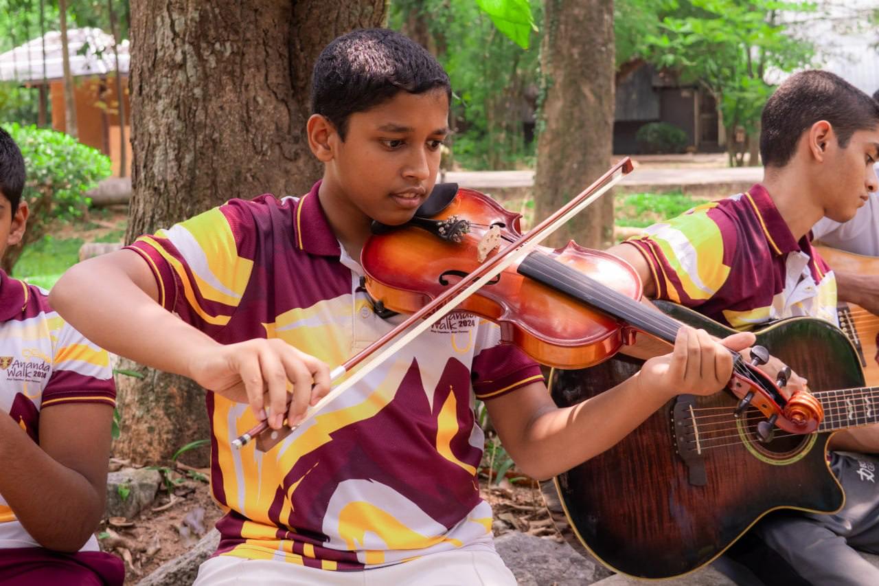 Young musicians perform in a tranquil park, violin and guitar under lush trees.