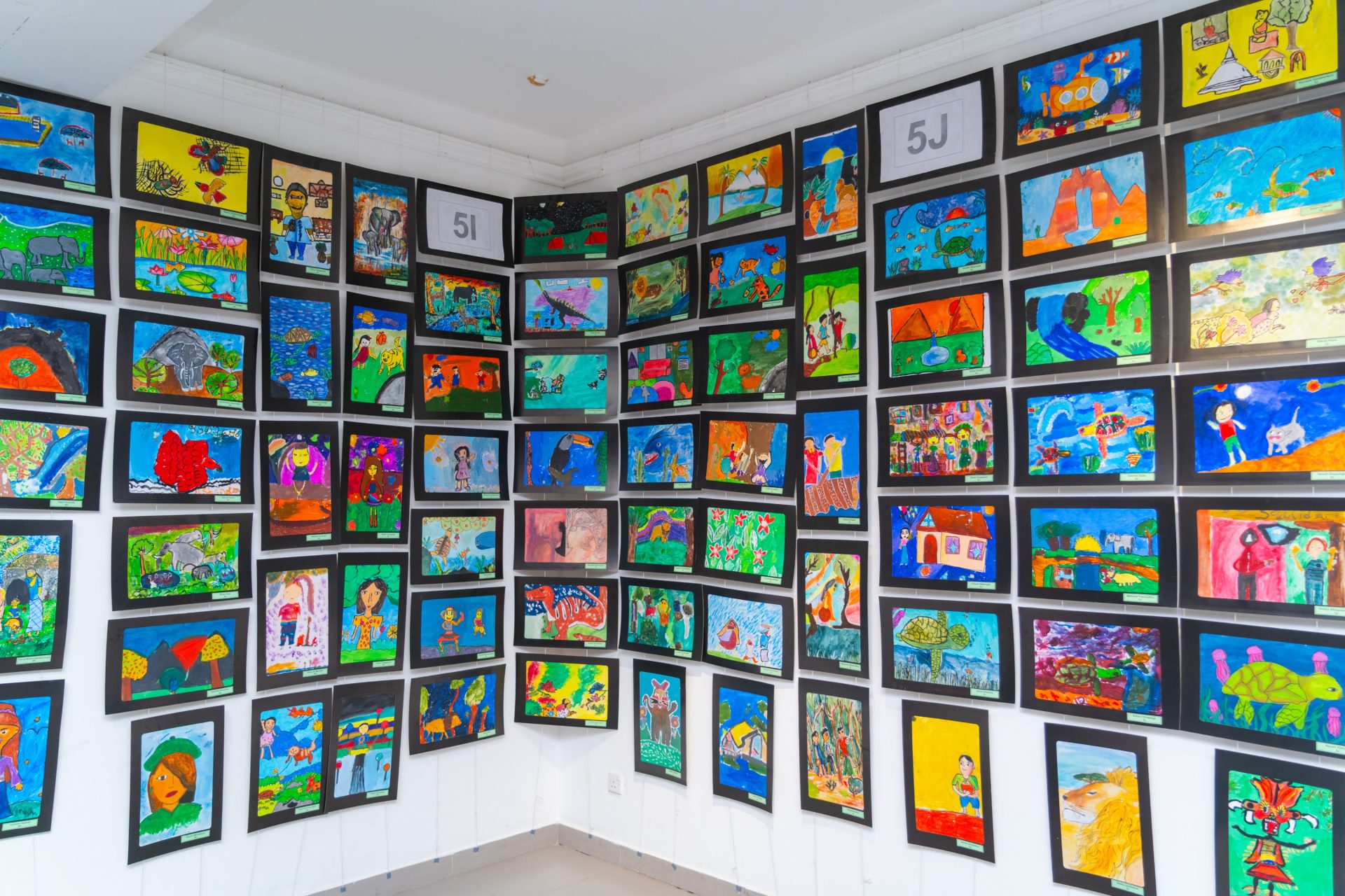 Corner classroom display of colorful student artwork, kids creative drawings, school art exhibit.