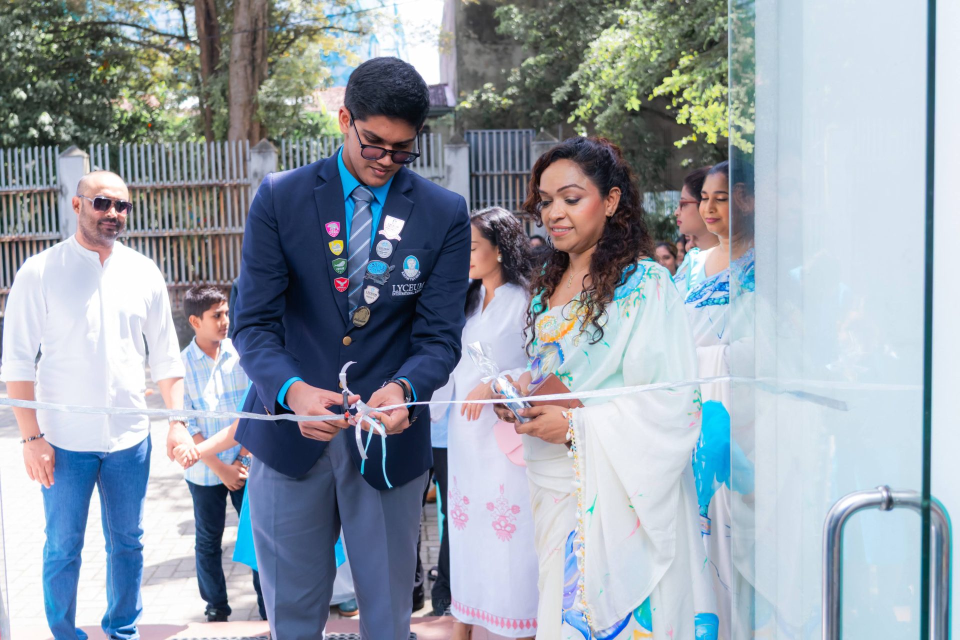 Lyceum School ribbon-cutting with student leader and staff, celebrating new facility opening outdoors.