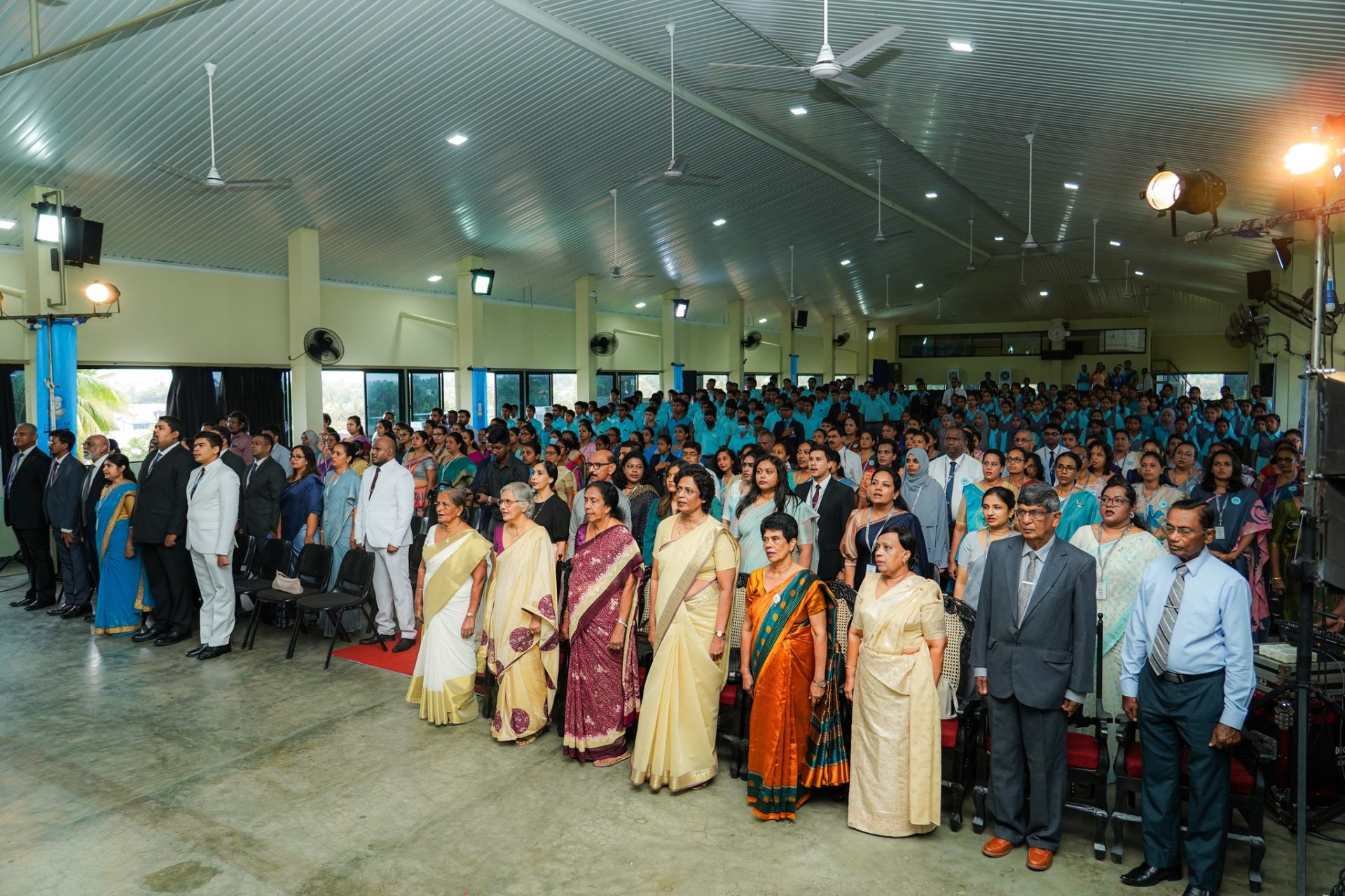 University Ceremony With Faculty, Dignitaries, and Students Standing Academic ceremony with dignitaries, faculty, and students in uniforms inside a large, modern hall.