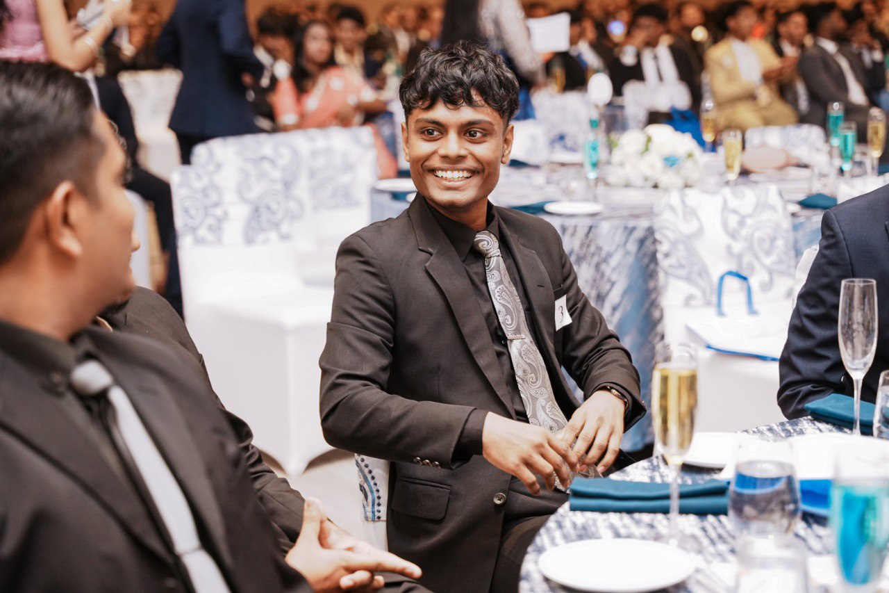 Young Professionals Enjoying a Formal Gala Dinner Event Young men in suits enjoying a formal banquet event with elegant table settings and decor.
