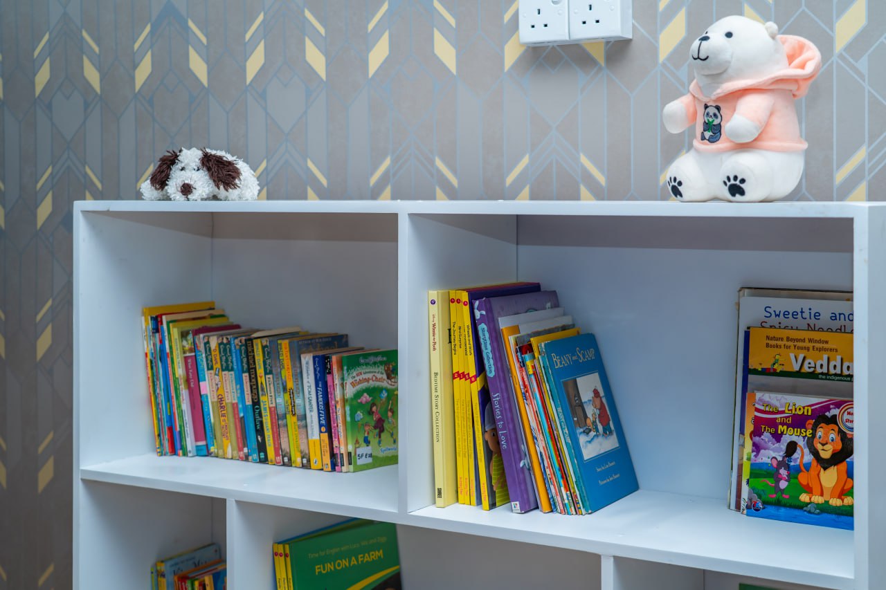 Children’s bookshelf with picture books, plush dog, polar bear, and cozy reading corner decor.