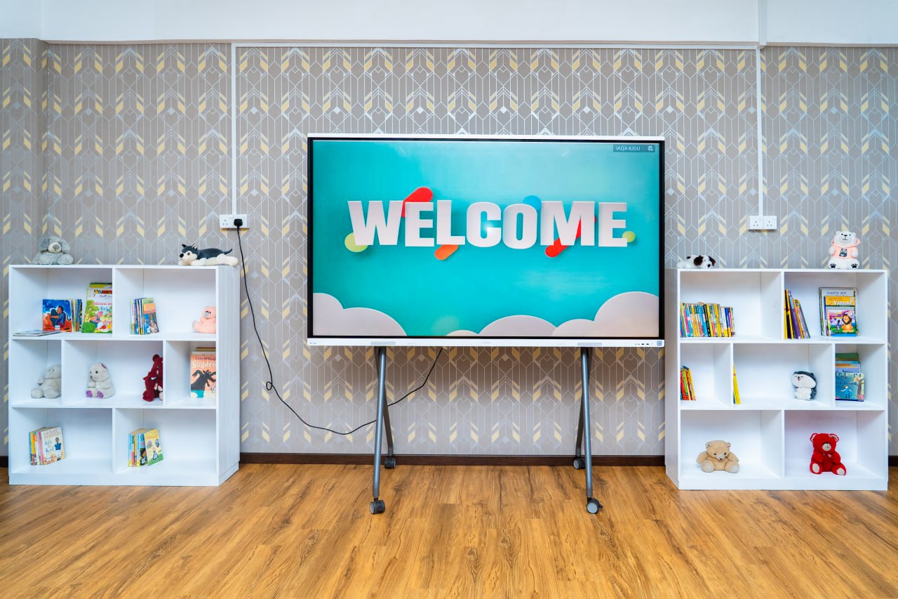 Children’s reading area with digital welcome screen, colorful books, stuffed animals, library, and learning space.