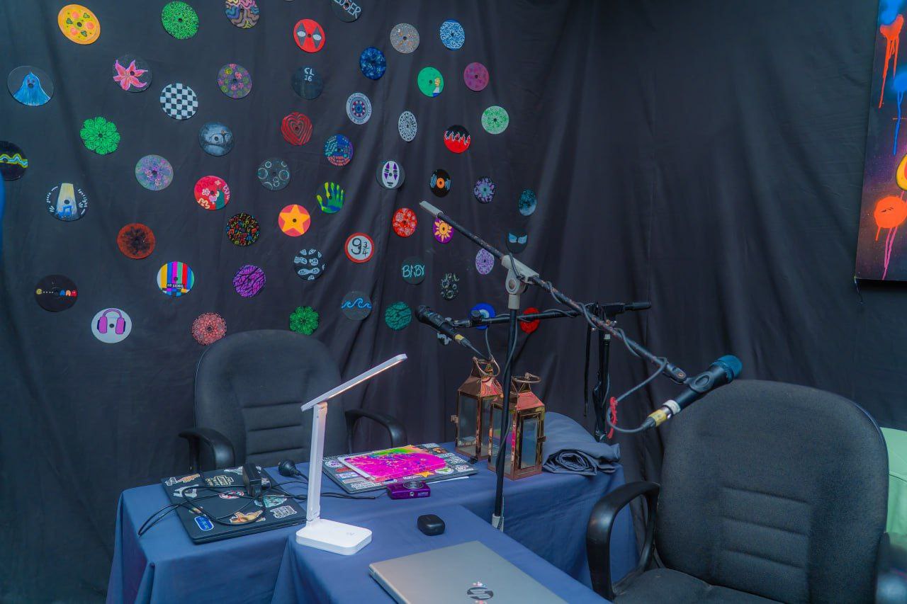 Creative podcast studio with microphones, laptops, artistic circular wall art, and audio recording equipment.