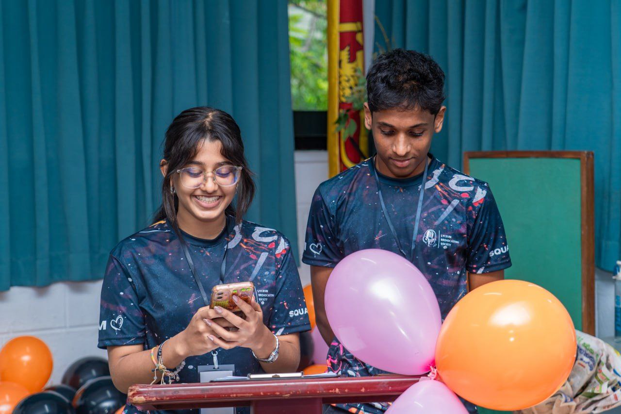 Two students at a podium with balloons, celebrating a school event in Sri Lanka.