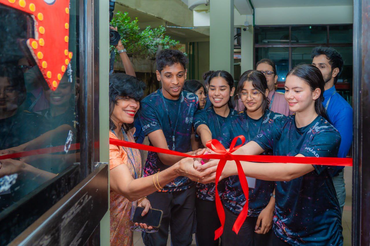 Ribbon-cutting ceremony with diverse team in galaxy T-shirts celebrating grand opening event.
