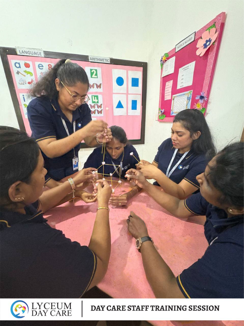 Daycare staff team-building activity with spaghetti and marshmallows during training in a preschool classroom.