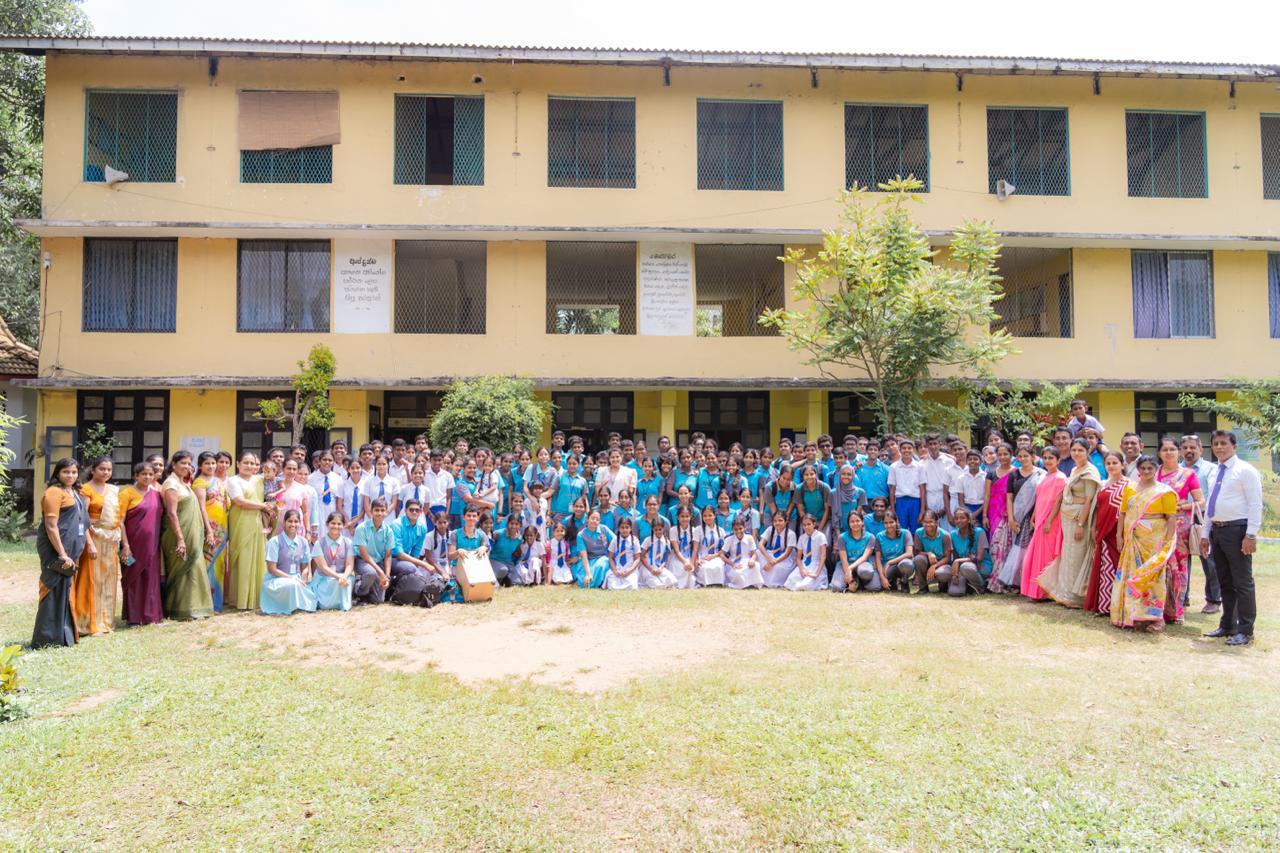 Indian school group photo outside yellow building, students and teachers in uniform, cultural event.