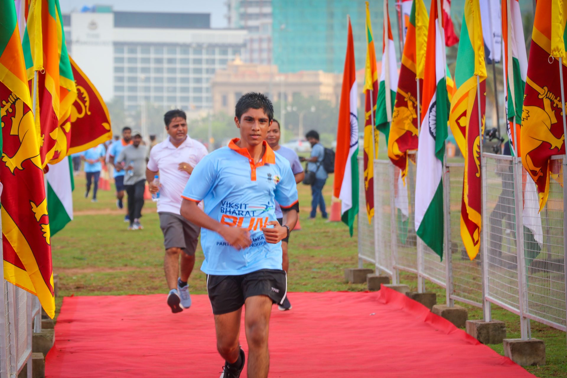Runner at Viksit Bharat marathon event with Indian and Sri Lankan flags in an urban park.