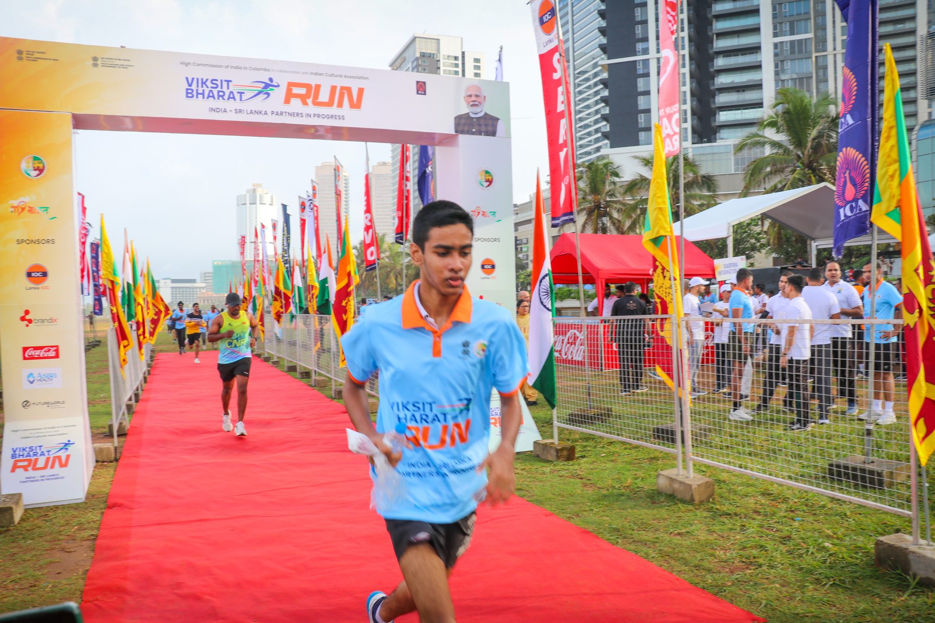 Viksit Bharat Run in Colombo with Indian and Sri Lankan flags, runners, finish line, and cheering crowd.