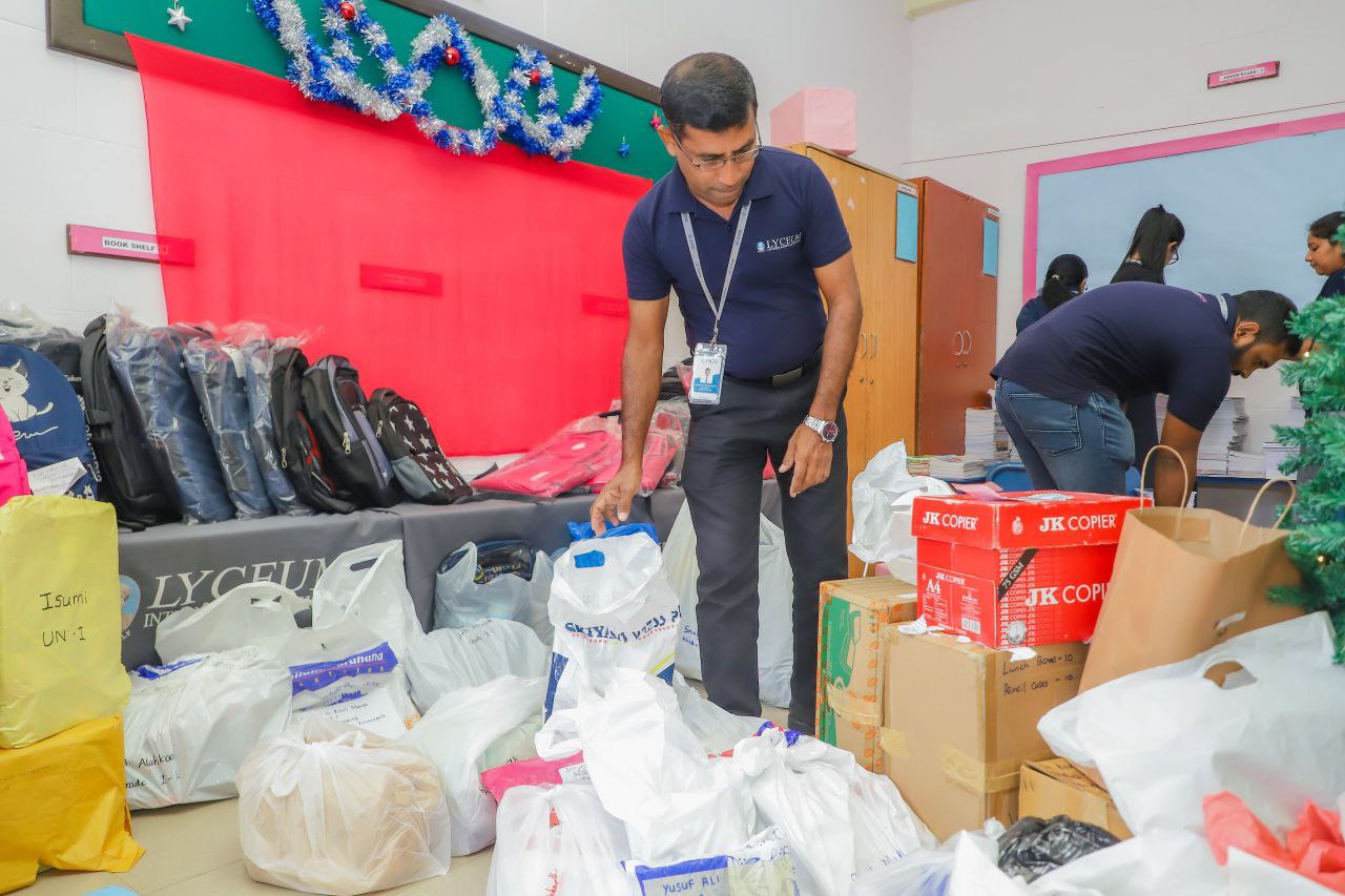 Lyceum school staff organizing Christmas donation drive supplies and gifts for community outreach event.