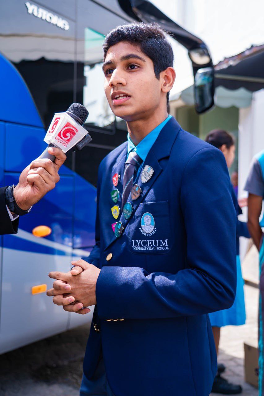 Lyceum International School student interviewed by local media during school event near bus.