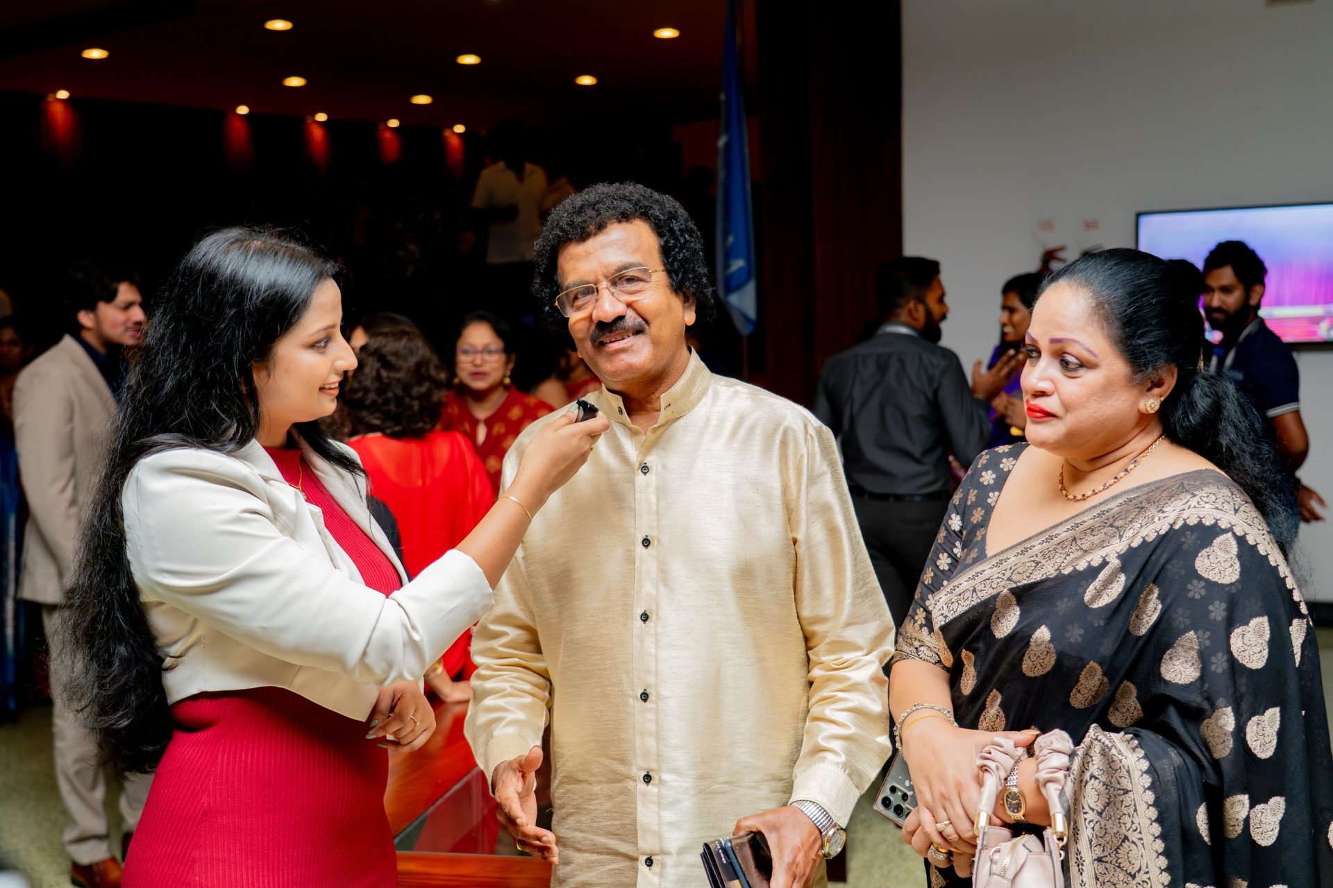 Indian formal event interview with elegantly dressed guests in saree and kurta during cultural celebration.