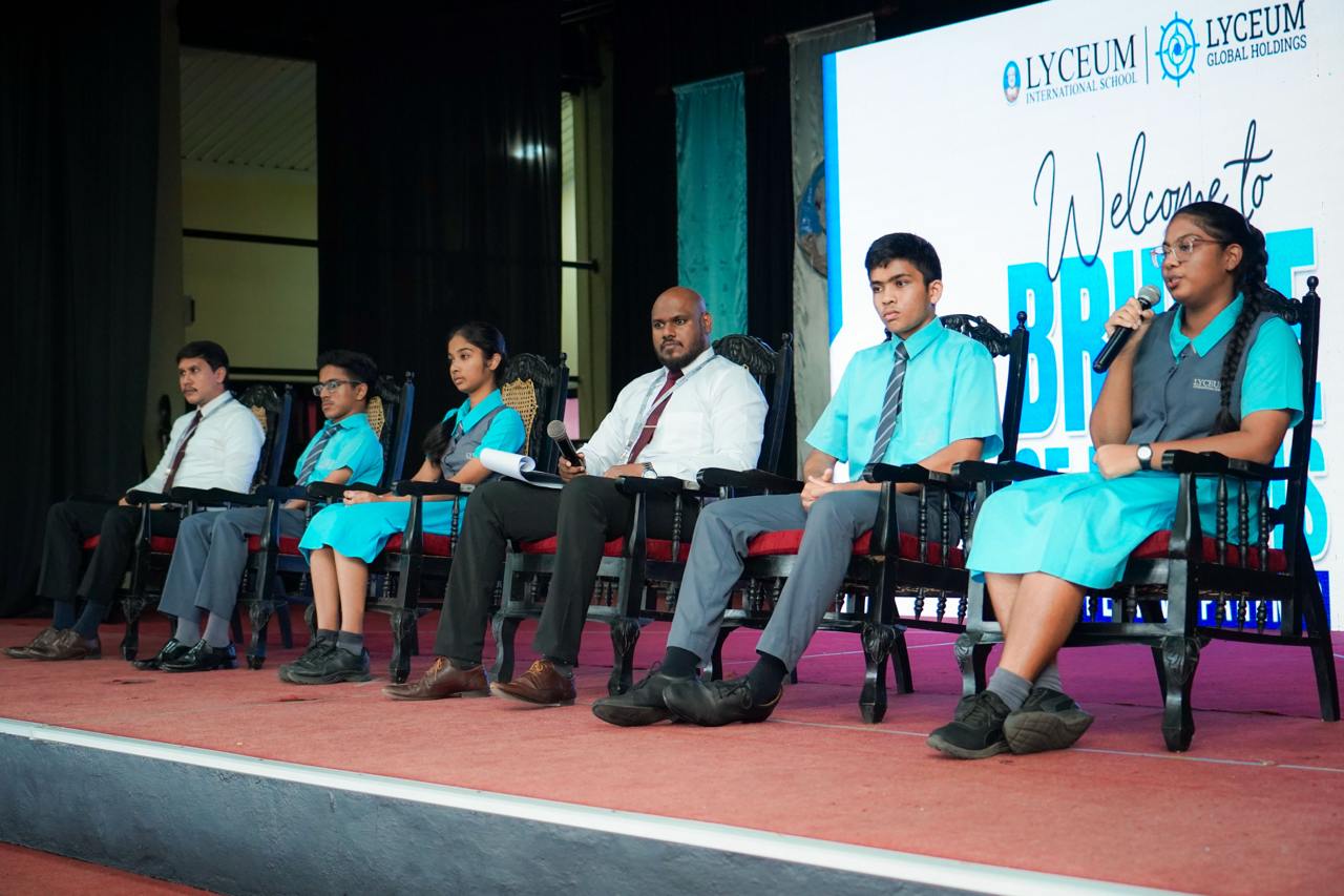 Lyceum International School students and faculty in leadership panel discussion on stage, school event.