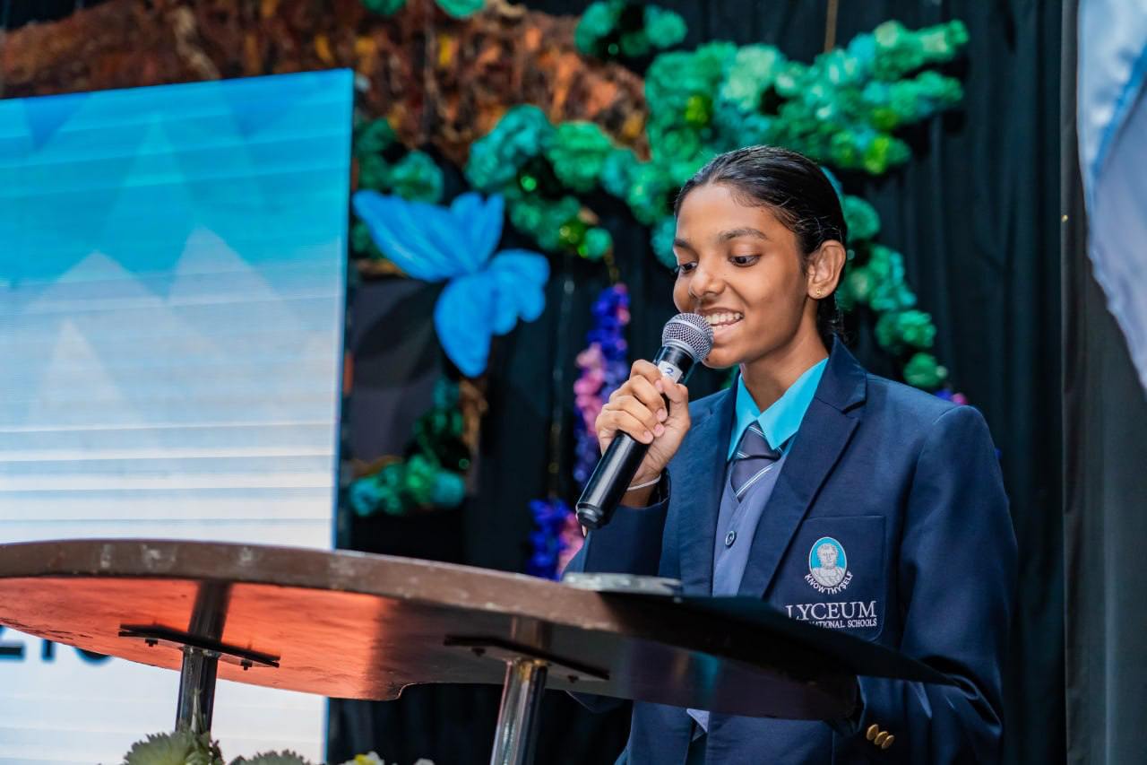 Student delivers speech at Lyceum International School event with vibrant, nature-inspired decorations.