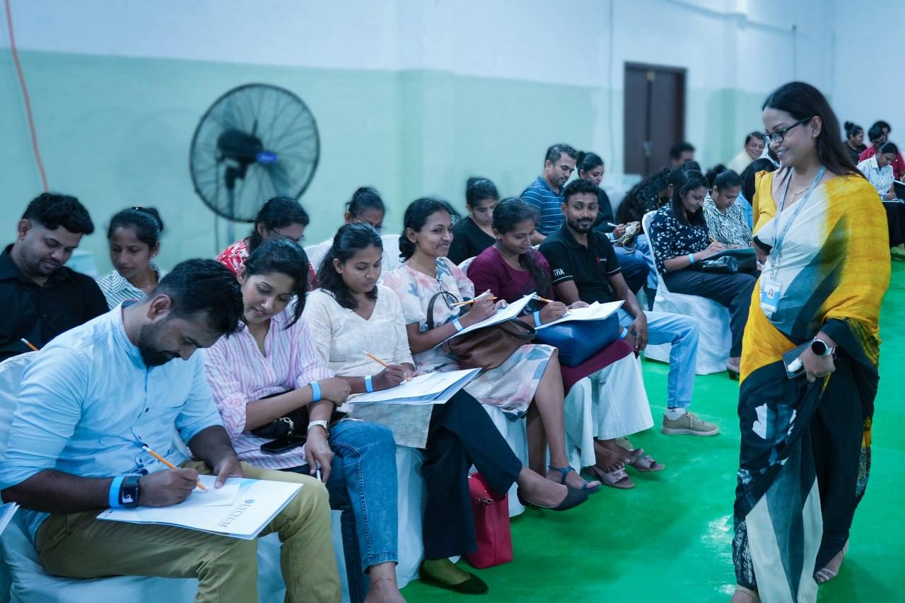 Students in classroom workshop attentively write as instructor in yellow observes and supports learning.
