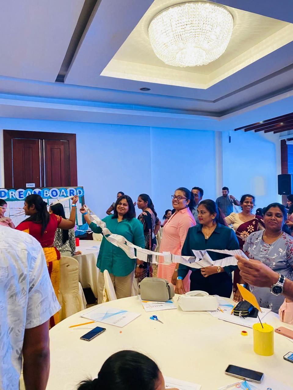 Women collaborate at a creative dream board workshop, crafting and bonding in a bright conference hall.