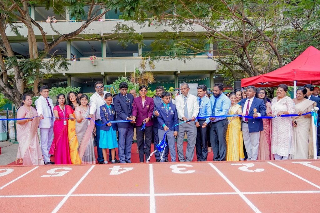 Ribbon-cutting ceremony with students, teachers, and dignitaries on a newly opened school running track.