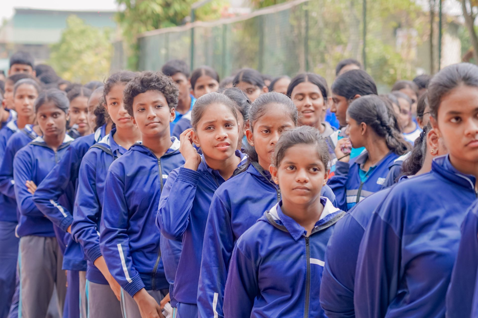 School girls in navy tracksuits lined up outdoors for a sports event or physical education class.