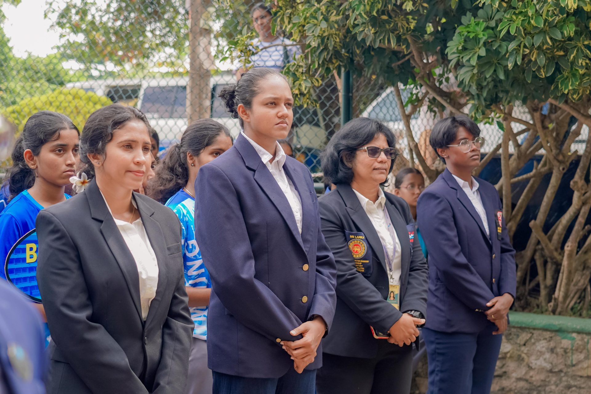 Sri Lankan women’s badminton officials and players at outdoor ceremony, showing team spirit and professionalism.