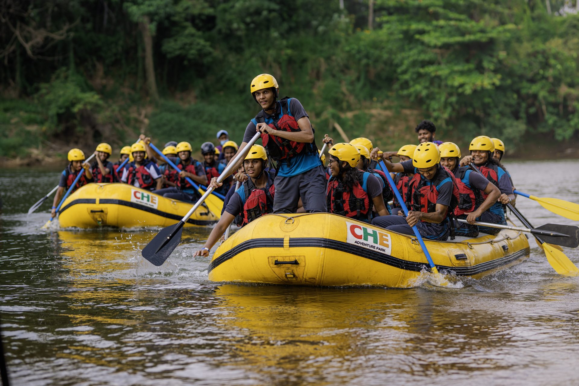 Group of people rafting in yellow boats on a scenic river at CHE Adventure Park.