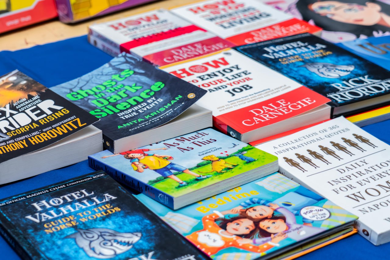 Colorful book display with childrens stories, self-help, adventure, and mythology at a book fair.