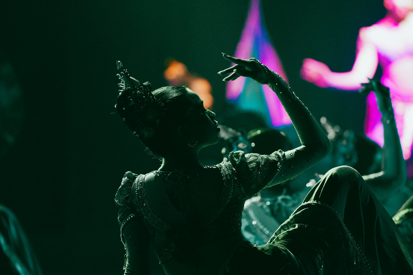 Elegant Southeast Asian Dancer in Vibrant Stage Lighting Southeast Asian traditional dancer in ornate costume, gracefully performing under colorful stage lighting.