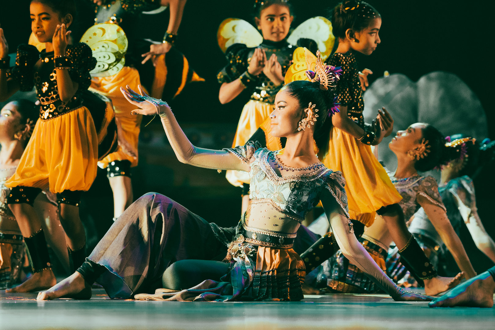 Elegant Cultural Dance in Vibrant Bee-Inspired Costumes Dancers in bee-inspired yellow and black costumes perform a graceful, synchronized cultural dance on stage.