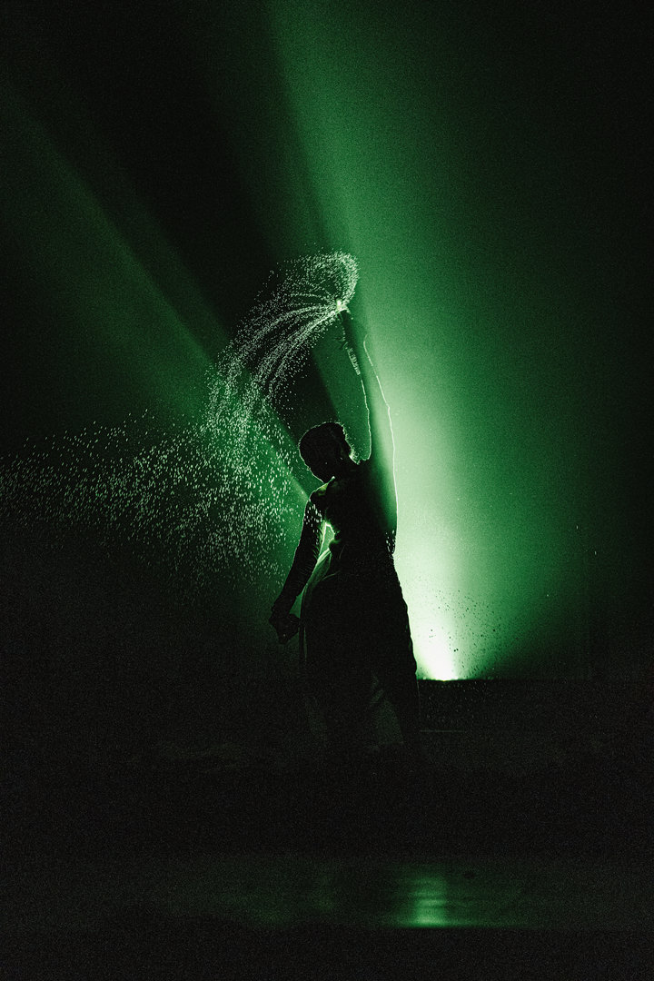 Luminous Green Silhouette Dance With Water Spray Silhouette dancer in vivid green light with water spray, contemporary performance art photography.